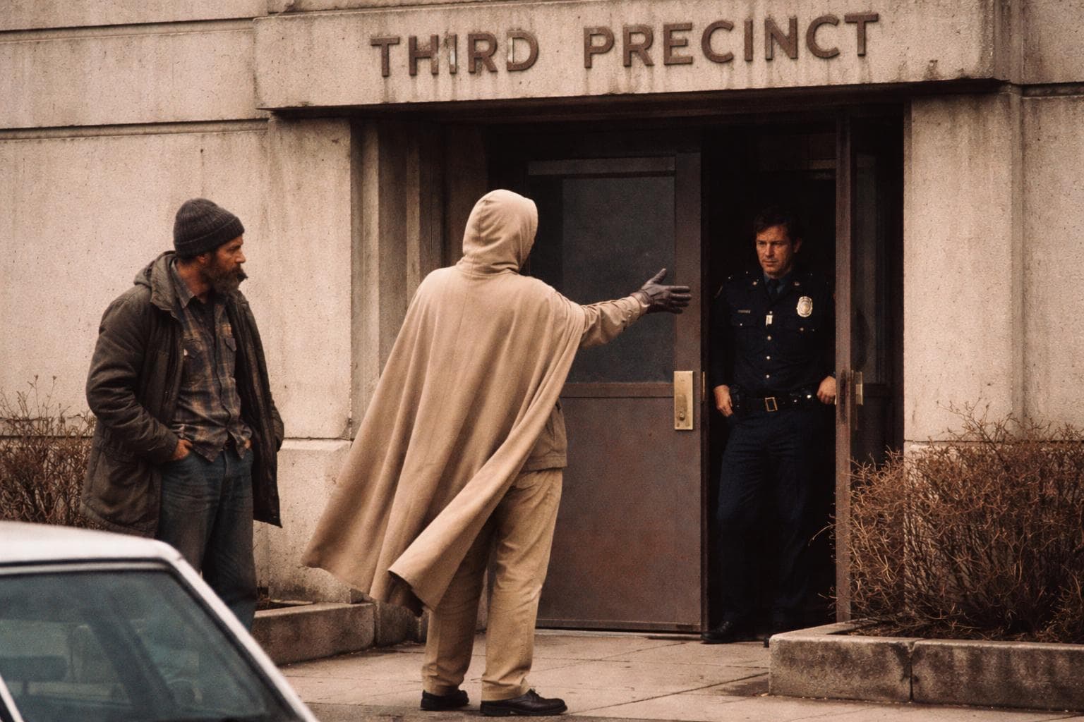 The costumed vigilante known as The Reasonable Middle delivers a citizen's detention outside the Third Precinct on Wednesday, beige cape visible.